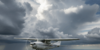 Small aircraft flying through spring weather with clouds